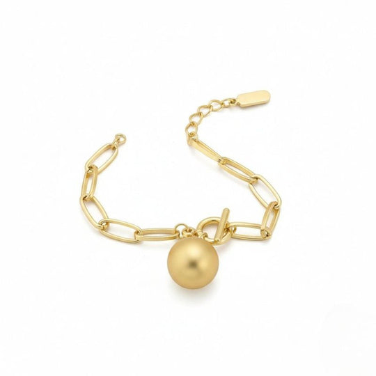 Goldfarbenes Damen-Gliederarmband mit Kugelanhänger, getragen am Handgelenk und in Nahaufnahme dargestellt