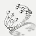 Damenarmband mit mehreren glatten Metallreihen und polierten Kugelenden, in Gold- oder Silberoptik am Handgelenk und in Detailansicht dargestellt