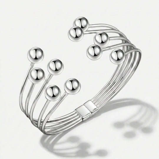 Damenarmband mit mehreren glatten Metallreihen und polierten Kugelenden, in Gold- oder Silberoptik am Handgelenk und in Detailansicht dargestellt