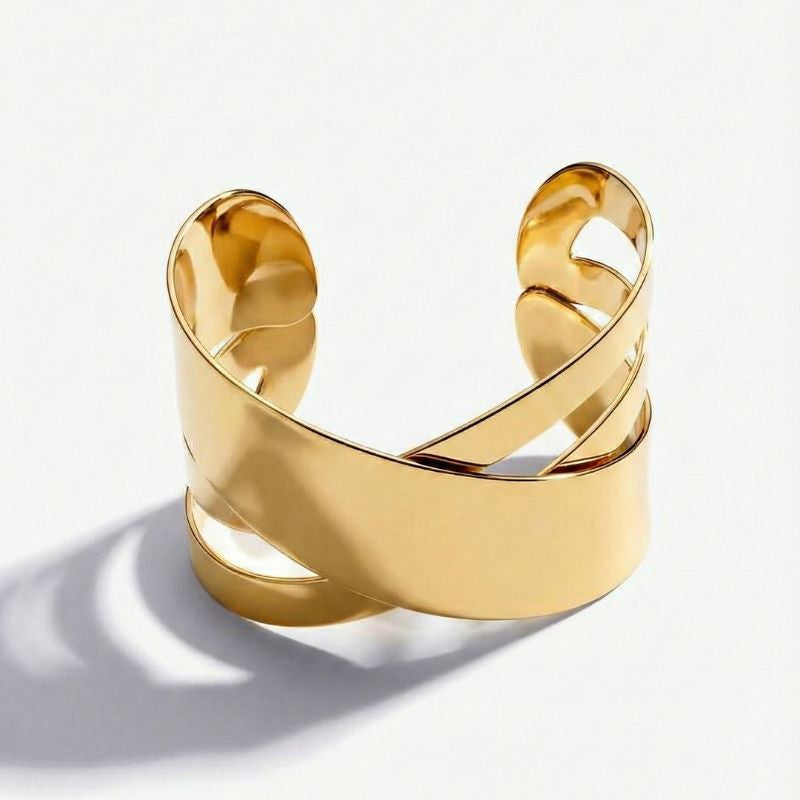 Goldfarbenes Damen-Armreif-Armband mit breitem Überkreuz-Design, getragen am Handgelenk und in Detailansicht dargestellt