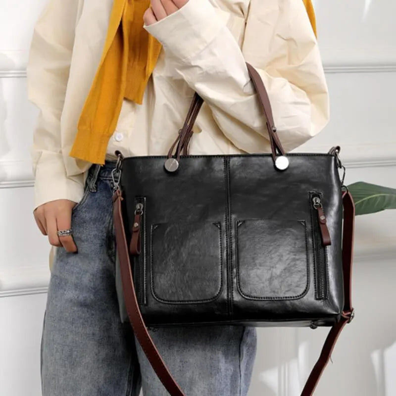Eine Frau trägt eine schwarze Ledertasche mit verstellbarem Riemen und mehreren Taschen