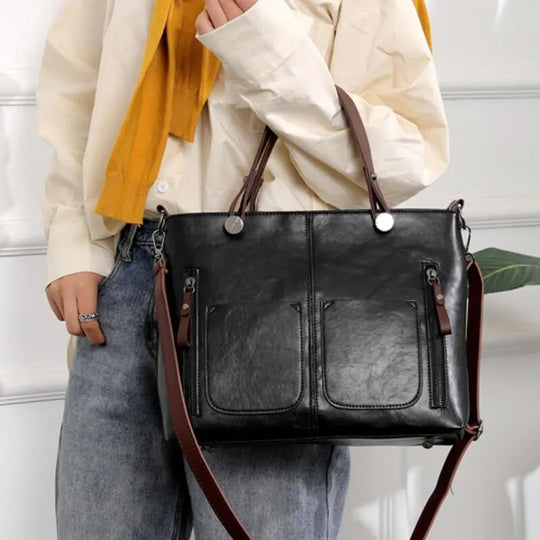 Eine Frau trägt eine schwarze Ledertasche mit verstellbarem Riemen und mehreren Taschen