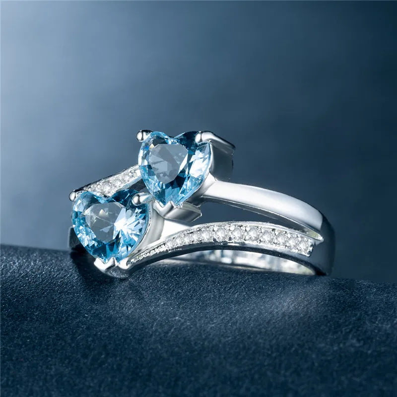 Damen herzförmiger Ring mit funkelnden Zirkonia und zwei blauen Edelsteinen Shop Nory