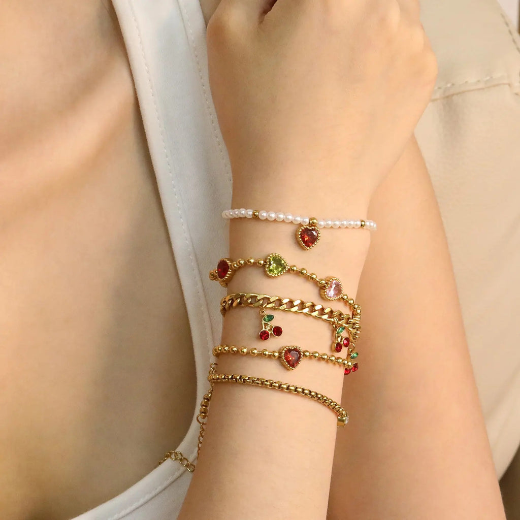 Damen Armband mit schimmernden goldenen Perlen und funkelndem Herzanhänger Shop Nory