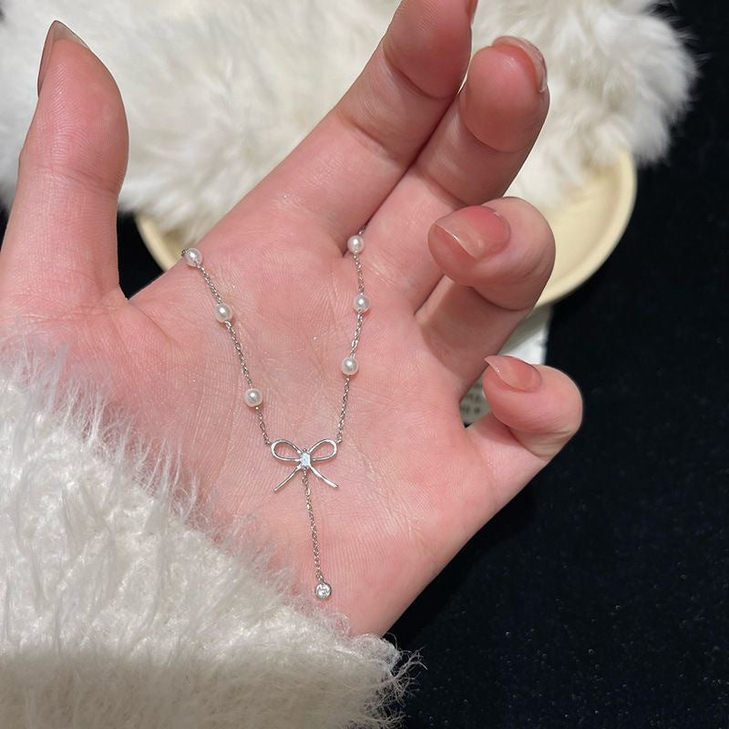 Damen Kette mit zartem Schleifenanhänger und eleganten Perlendetails Shop Nory