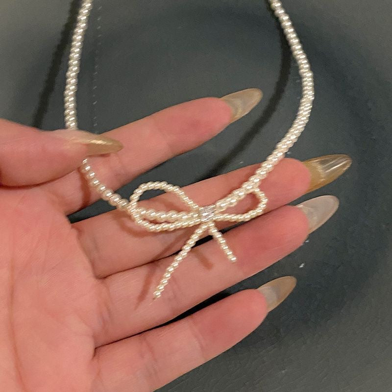 Damen Halskette mit elegantem Schleifenanhänger und zarten Perlendetails Shop Nory