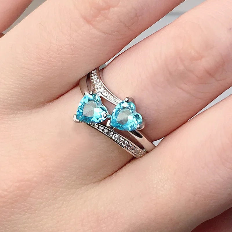 Damen herzförmiger Ring mit funkelnden Zirkonia und zwei blauen Edelsteinen Shop Nory
