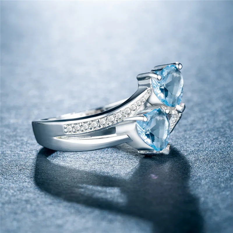 Damen herzförmiger Ring mit funkelnden Zirkonia und zwei blauen Edelsteinen Shop Nory