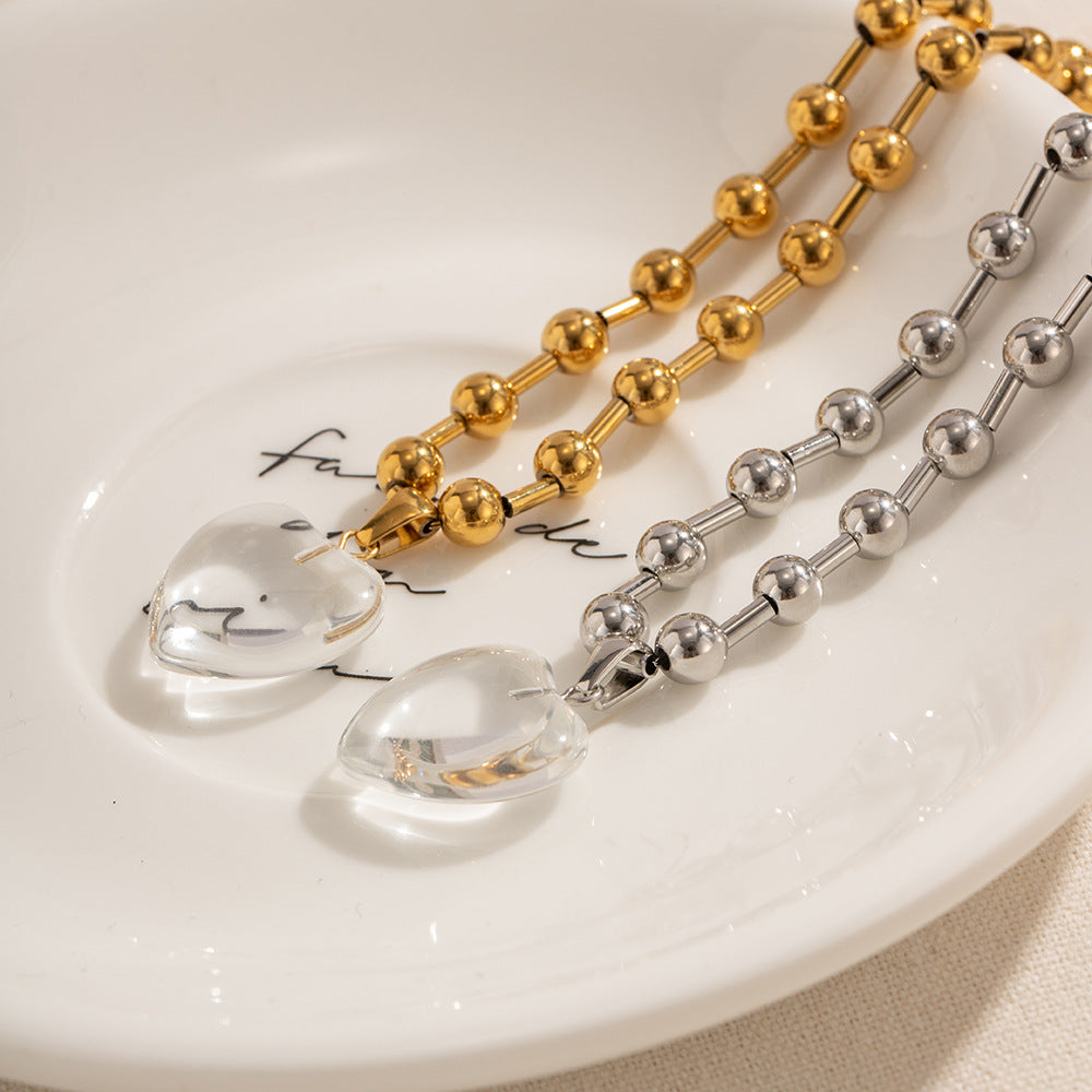 Damen Halskette mit transparentem Herzanhänger und goldene Kugel-Details Shop Nory