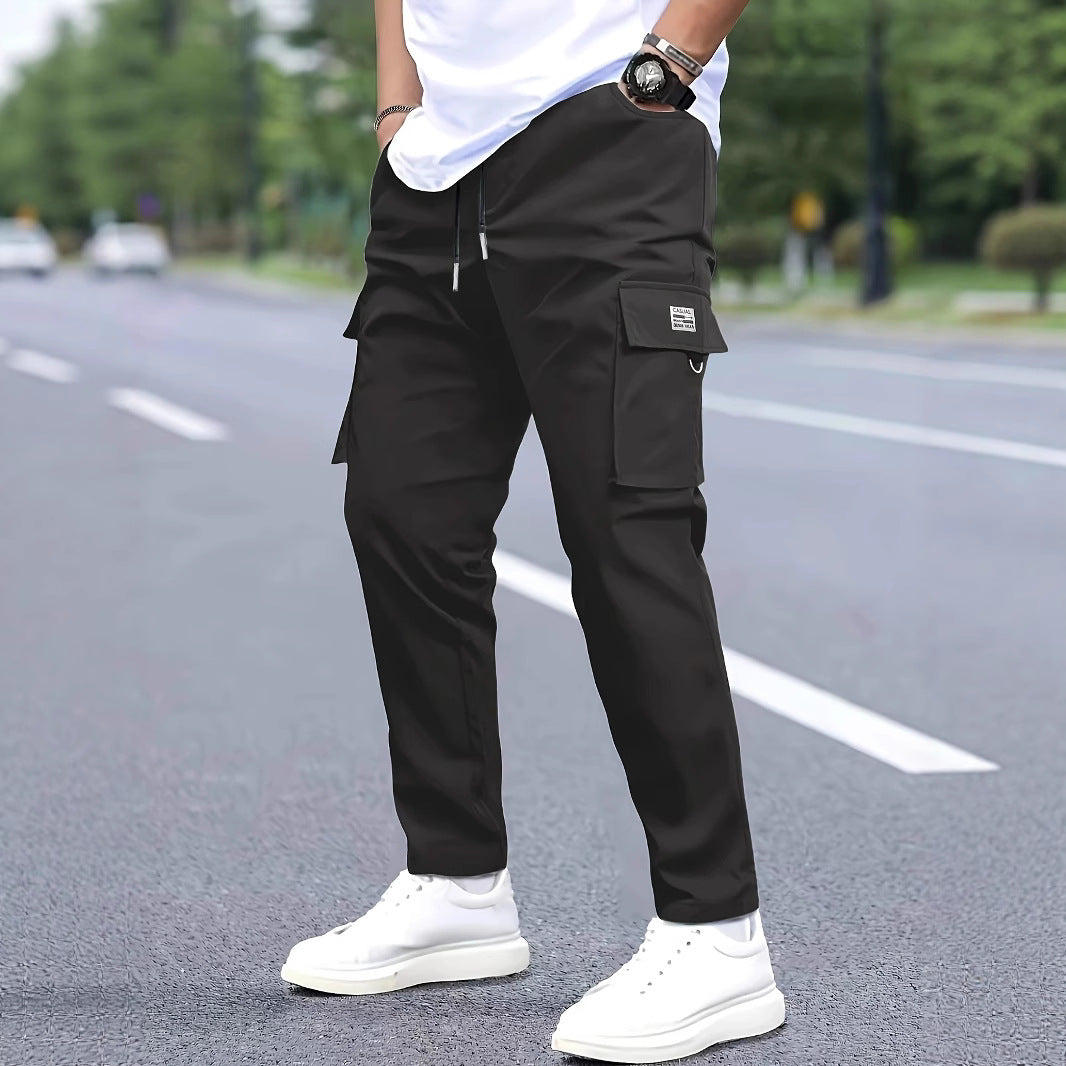 Herren Slim‑Tapered Cargo‑Jogginghose mit Tunnelzugbund, Klappentaschen und Metallringdetail Shop Nory