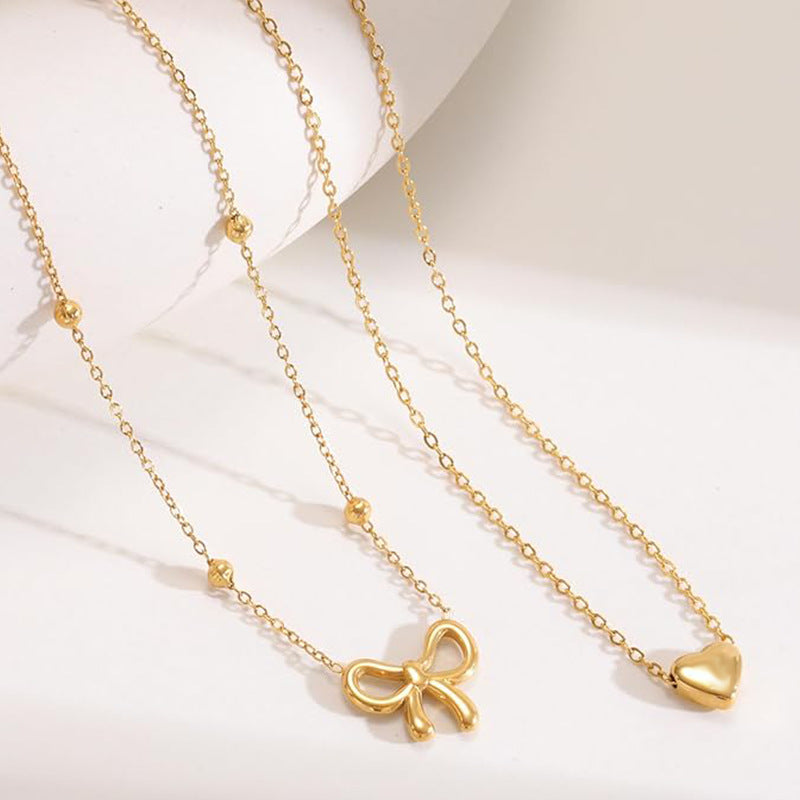 Damen Halskette mit doppellagigem Design und zarten Herz- und Schleifenanhängern Shop Nory