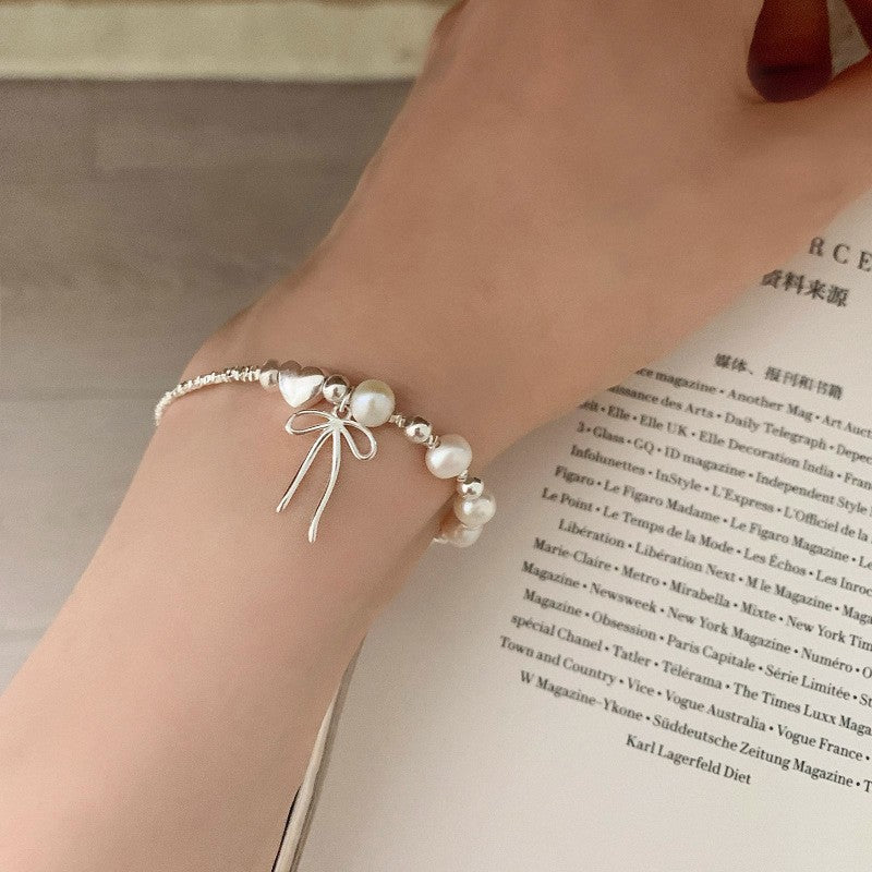 Damen Schmuckarmband mit filigranem Schleifenanhänger und hochwertigen Perlen Shop Nory