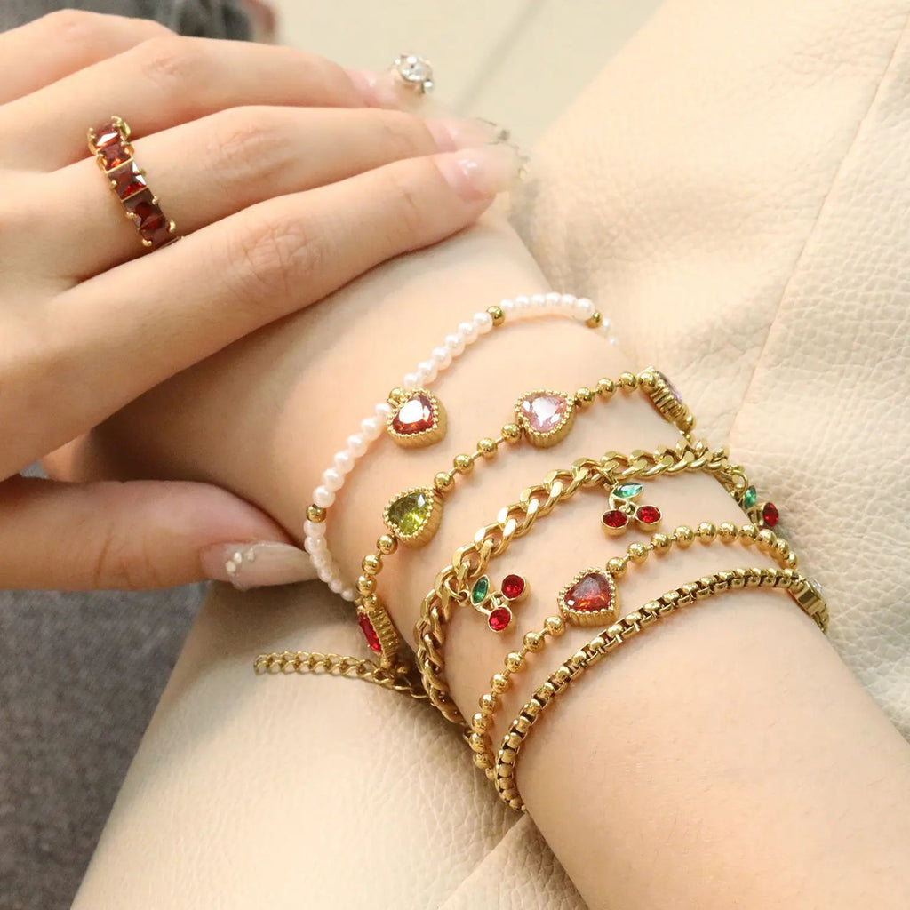 Damen Armband mit schimmernden goldenen Perlen und funkelndem Herzanhänger Shop Nory