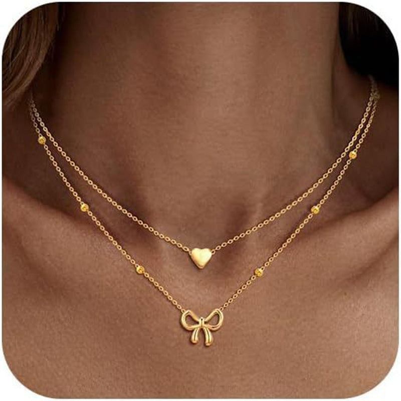 Damen Halskette mit doppellagigem Design und zarten Herz- und Schleifenanhängern Shop Nory