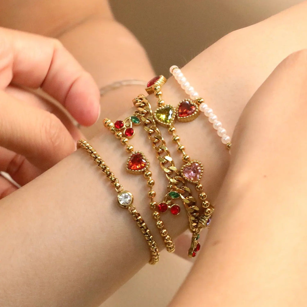 Damen Armband mit schimmernden goldenen Perlen und funkelndem Herzanhänger Shop Nory