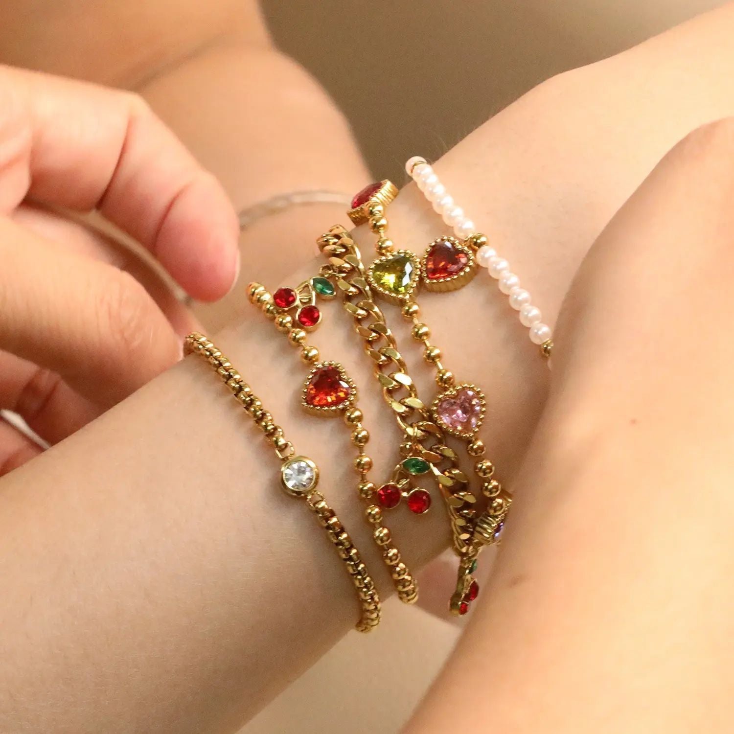 Damen Armband mit schimmernden goldenen Perlen und funkelndem Herzanhänger Shop Nory