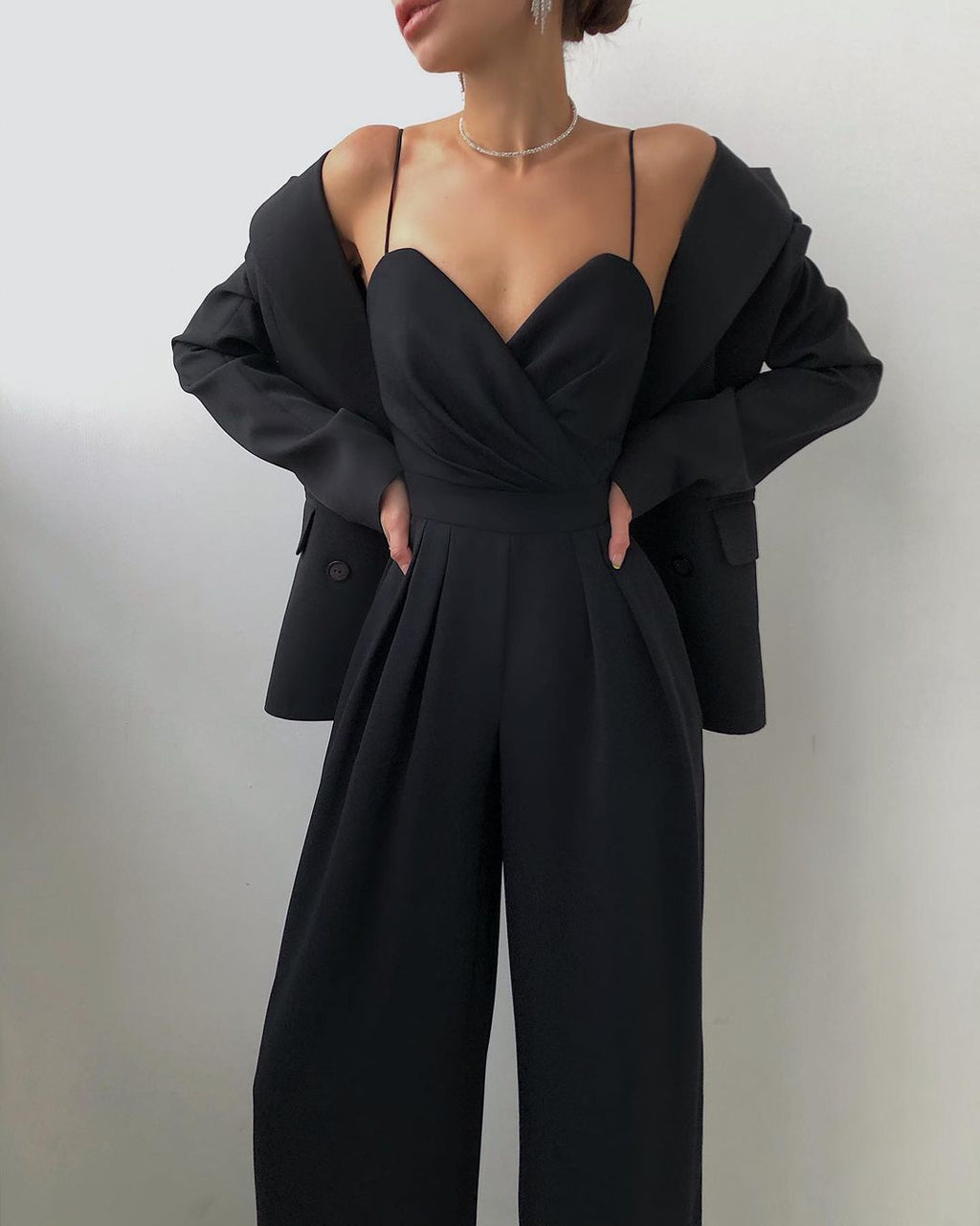 Ein modell in einem schwarz sexy riemen-overall und blazer